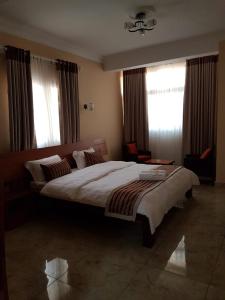 a bedroom with a large bed and two windows at Select Hôtel in Morondava