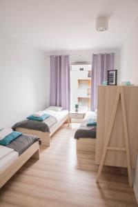 drie bedden in een kamer met paarse gordijnen bij MSapartamenty Centrum in Poznań