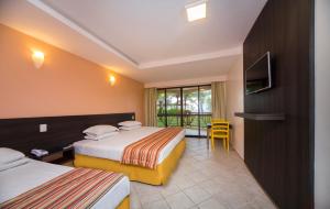 Makai Resort All Inclusive Convention Aracaju في أراكاجو: غرفه فندقيه سريرين وتلفزيون
