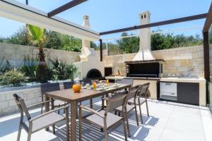 an outdoor kitchen with a wooden table and chairs at Villa Thalia in Stalos