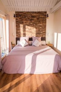 a large white bed in a room with a brick wall at La Vie en Rose - a fully equipped pet friendly contactless house with fenced garden between the fields in Torhout