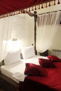 ロストフ・ナ・ドヌにあるブティックホテル プロムナードのベッドルーム1室(白いシーツと赤い枕のベッド1台付)