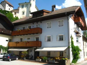 un edificio blanco con balcones y un coche aparcado delante en Gasthof Obermair, en Chienes