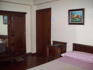 a bedroom with a bed and a wooden cabinet at Pensión Los Pinos Gijón in Gijón