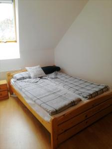 drewnianym łóżkiem w pokoju z oknem w obiekcie Centrum - A. Apartman w mieście Pecz