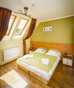 a bedroom with a large bed and two windows at Natural Panzió in Győr