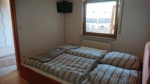 Bett in einer Ecke eines Zimmers mit Fenster in der Unterkunft Gasthaus zum Löwen in Seckach