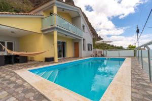 a swimming pool in front of a house at The Blue Pearl-Villa Paul in Calheta