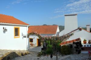 Uma casa branca com um banco à frente. em Quinta do Bom Vento em Óbidos