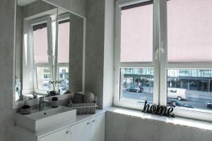 ein Badezimmer mit einem Waschbecken und zwei Fenstern in der Unterkunft Novel in Warschau