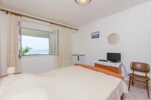 a white bedroom with a bed and a window at Apartments and Room Mate-Mare in Primošten