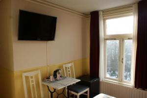 a room with a table and a television on the wall at Hotel de Westertoren in Amsterdam