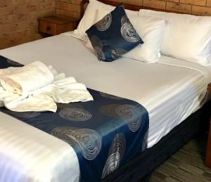 2 camas con sábanas blancas y almohadas azules y blancas en James Street Motor Inn, en Toowoomba