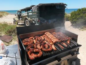 a grill with a bunch of sausages and sausage at Desert Tracks Rancho in Las Grutas