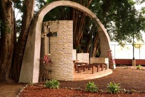 un arco de piedra con mesas y bancos en un parque en Playa Almendro Resort, en Tonsupa