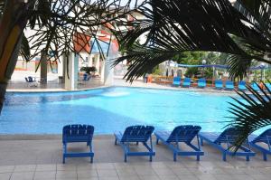 a group of blue chairs and a swimming pool at Playa Almendro Resort in Tonsupa