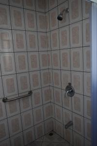 um chuveiro com duas cabeças de chuveiro numa parede de azulejos em Hotel Las Brumas em Cartago