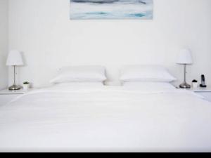 a bedroom with a white bed with two lamps at Bijoux Beach House in Freshwater