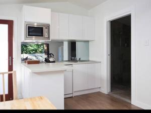 a kitchen with white cabinets and a microwave at Bijoux Beach House in Freshwater