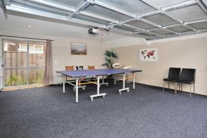 a ping pong table in a room with chairs at Regents Villas - Christchurch Holiday Homes in Christchurch