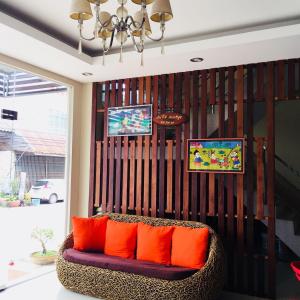 een woonkamer met een bank met oranje kussens bij Ratchanee Place in Chaiyaphum