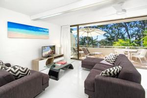 un soggiorno con divano, TV e balcone di Cove Point Apartment 2, Little Cove a Noosa Heads