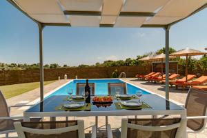 uma mesa com copos de vinho num pátio com piscina em Villa Antia em Metaxáta