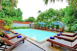una grande piscina con sedie e ombrelloni di Shewe Wana Suite Resort a Chiang Mai