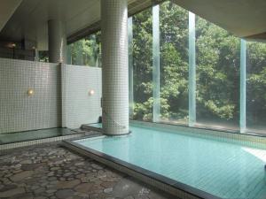 a swimming pool in a building with windows at Kikuchi Kanko Hotel in Kikuchi