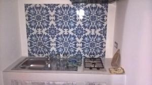 a kitchen with a sink and a blue and white wallpaper at Angel home in Malfa