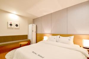 una camera da letto con un grande letto con lenzuola bianche di Blanc Business Hotel a Busan