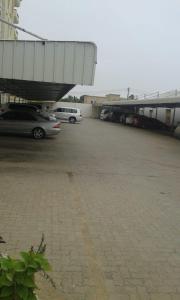 um parque de estacionamento com carros estacionados ao lado de um edifício em Ganaen Salalah em Salalah