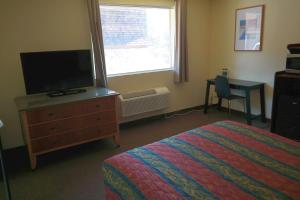 a bedroom with a bed and a television and a window at River Park Inn in Klamath Falls