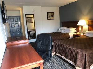 um quarto de hotel com duas camas, uma secretária e uma cadeira em Knights Inn Dayton by Miller Lane em Dayton