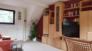 a living room with a tv and wooden book shelves at Ferienwohnung "Waldfrieden" in Altdöbern