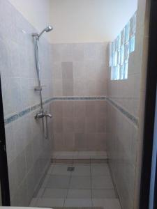 a bathroom with a shower and a tiled floor at Les pélerins in Pointe-Noire
