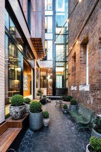 une cour avec bancs et plantes en pot dans un bâtiment dans l'établissement Crystalbrook Albion, à Sydney