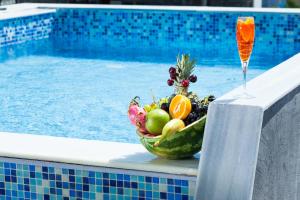 a bowl of fruit and a glass of juice next to a swimming pool at Nymphes Deluxe Accommodation Pefkochori in Pefkohori