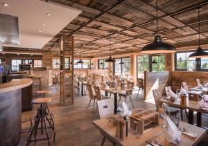 un restaurante con mesas y sillas de madera y ventanas en Alpin Chalets Oberjoch - Luxus Unterkunft mit privatem SPA und Zugang zu 3000 qm SPA Panoramahotel Oberjoch en Bad Hindelang