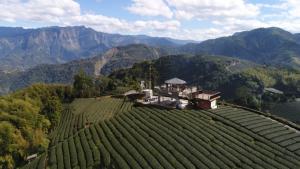 una casa en una colina con montañas en el fondo en lai Home Country Cottage B&B en Meishan