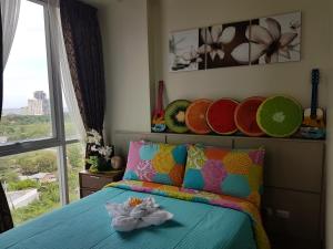 a bedroom with a bed with colorful pillows and a window at Mactan Newtown Ocean View 360 Degree in Mactan