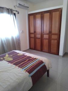 a bedroom with a bed and wooden cabinets at Les pélerins in Pointe-Noire