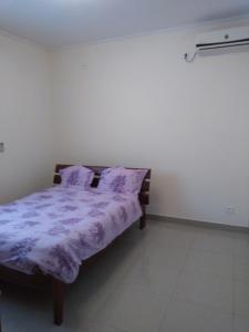 - une chambre avec un lit et une couette violette dans l'établissement Les pélerins, à Pointe-Noire