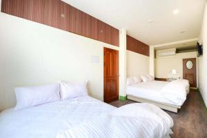 2 bedden in een kamer met witte lakens bij 小琉球觀海洋客棧View Ocean Inn in Xiaoliuqiu