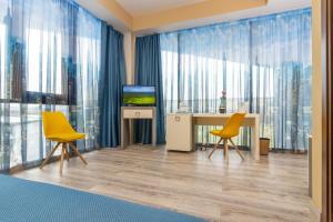 um quarto com duas cadeiras amarelas e uma mesa com televisão em West City Hotel em Cluj-Napoca