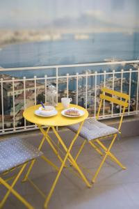 una mesa amarilla y sillas en un balcón con vistas en La Casa di Luna, en Nápoles