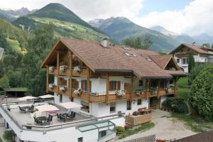 una casa en las montañas con mesas y sillas en Hotel Garni Angerer, en Lutago