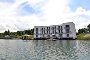 un grande edificio bianco, seduto sopra un corpo d'acqua di Laguna Seeappartements a Neukieritzsch
