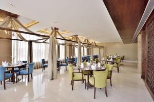 a dining room with tables and chairs and windows at Country Inn & Suites by Radisson Kota in Kota