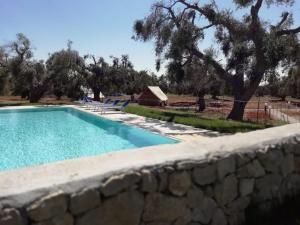 a swimming pool next to a stone wall at Agriturismo Marconi in Porto Cesareo